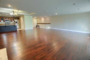 Unfurnished living room featuring recessed lighting, dark wood-type flooring, and a chandelier
