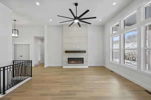 Unfurnished living room featuring light wood-style flooring, recessed lighting, a ceiling fan, and a large fireplace