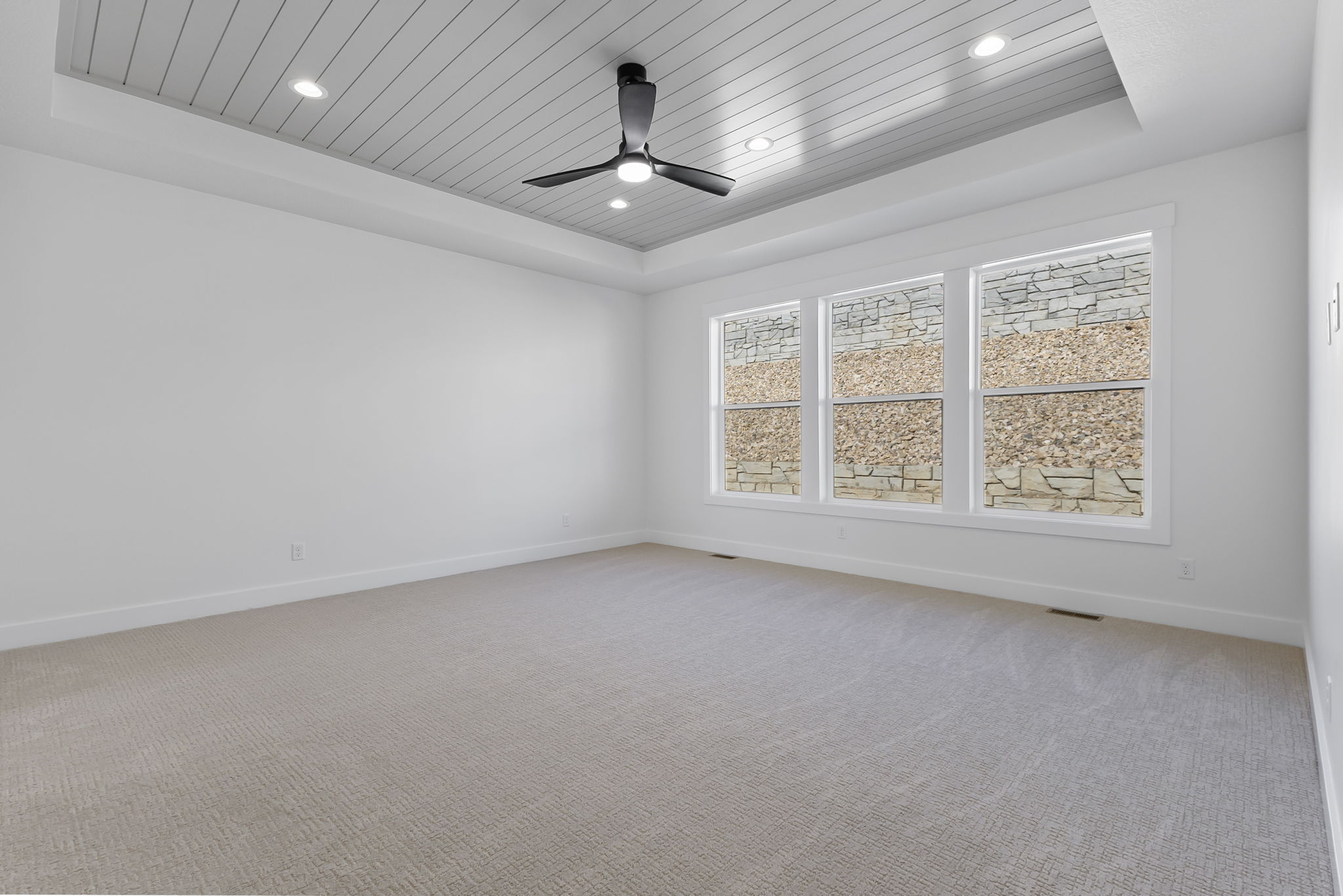 Empty room with a tray ceiling, light carpet, wooden ceiling, ceiling fan, and recessed lighting