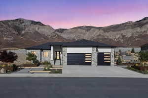Enhanced photo (Landscape not included) Contemporary home with a garage, a mountain view, driveway, and stone siding