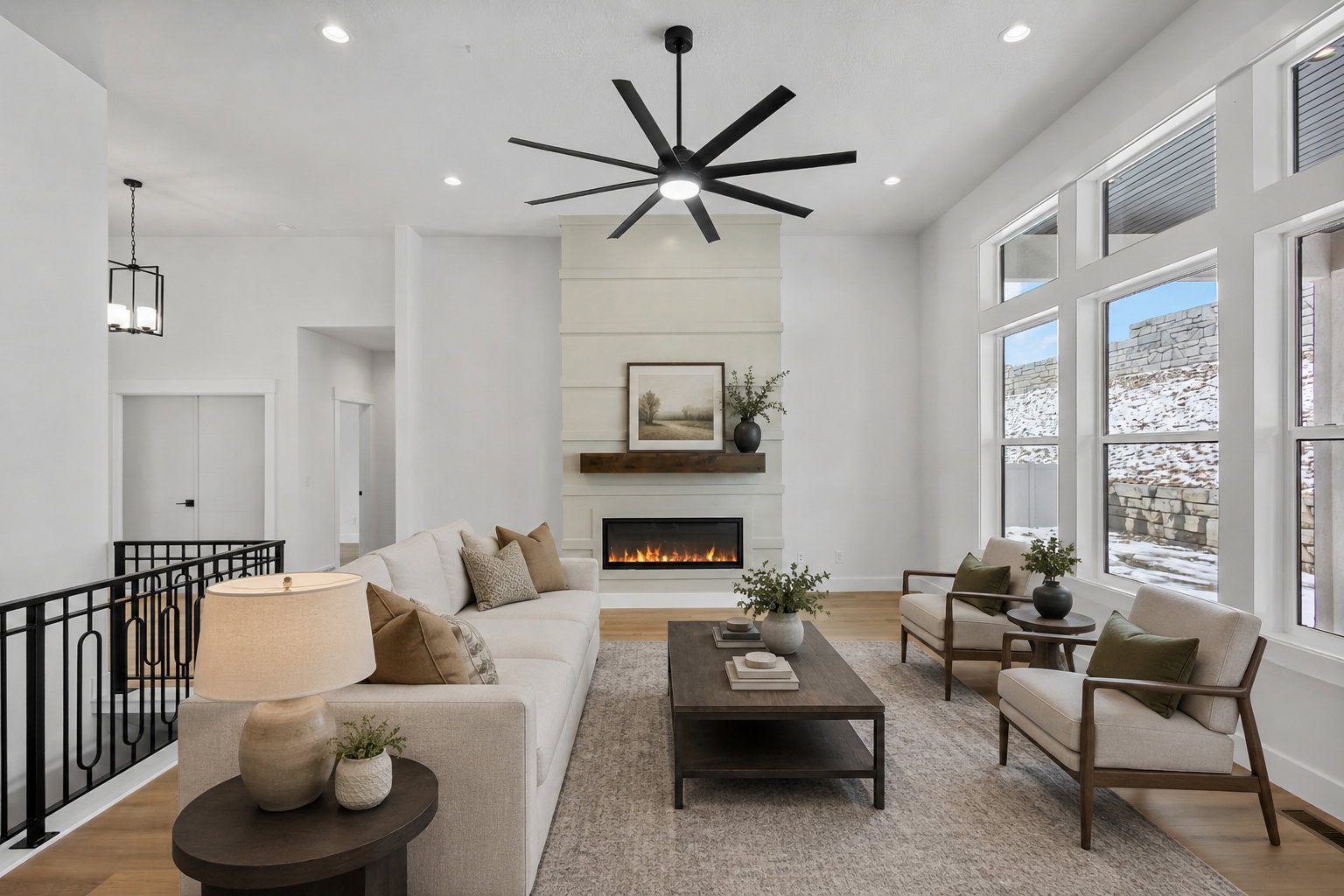 Living area featuring a floor-to-ceiling fireplace with a wood mantle and linear electric insert, expansive windows, wood-finish flooring, and a contemporary ceiling fan