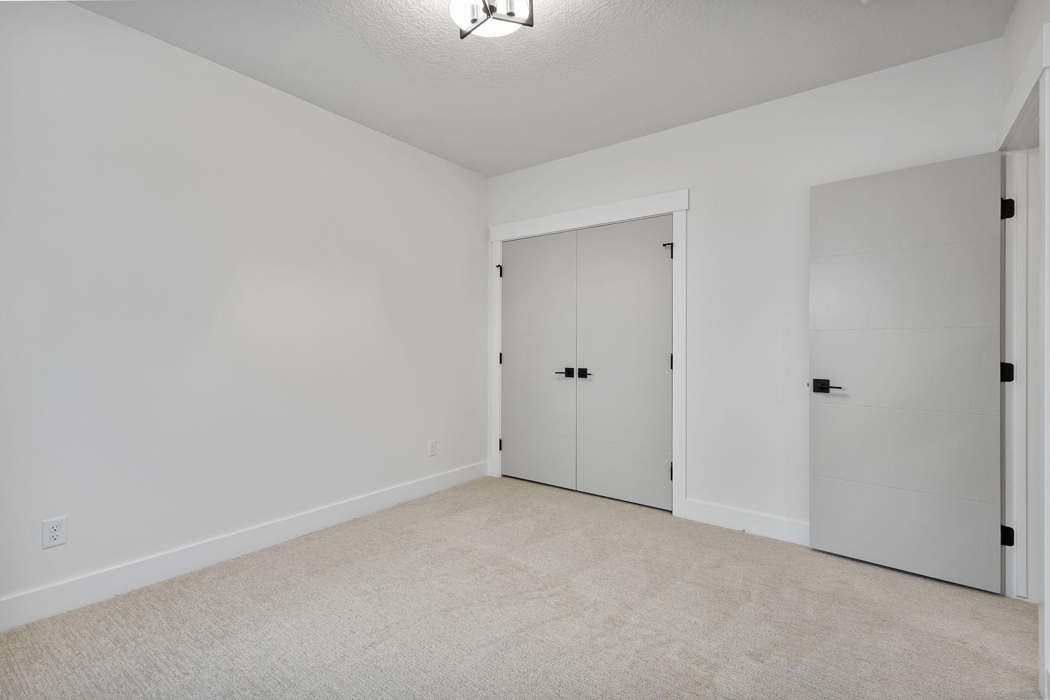 Room featuring light neutral-toned carpeting, white walls, and a modern ceiling light fixture