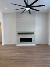 Unfurnished living room with recessed lighting, a ceiling fan, wood finished floors, and a fireplace