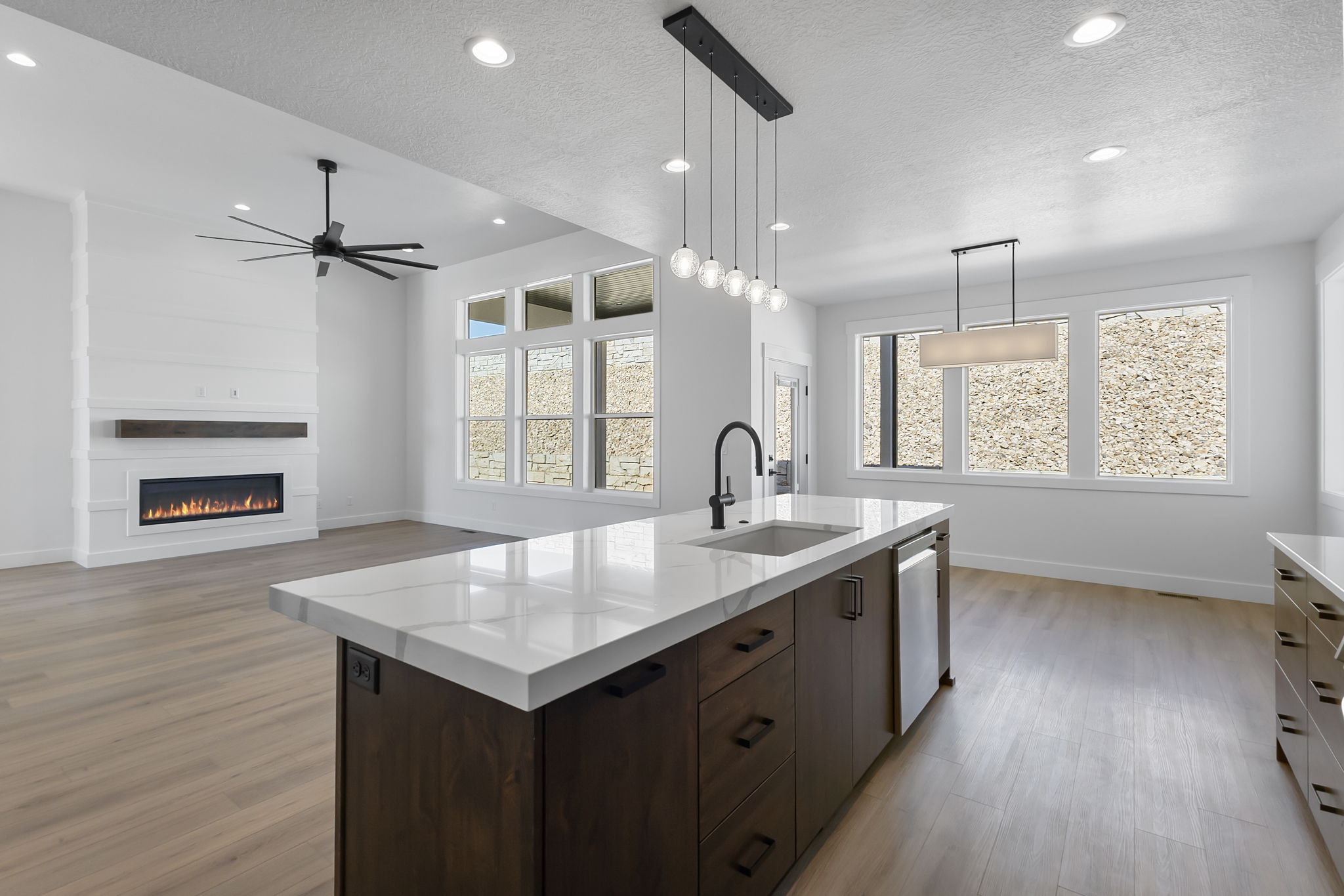Kitchen with dark brown cabinetry, pendant lighting, a textured ceiling, an island with sink, and ceiling fan