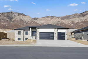 View of front of property with a mountain view, concrete driveway, a garage, and a shingled roof