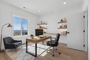 Enhanced staged photo Home office with light wood-style flooring and recessed lighting
