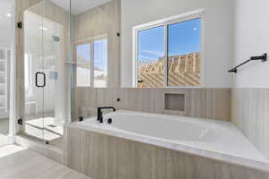 Full bathroom with a stall shower, a bath, and plenty of natural light