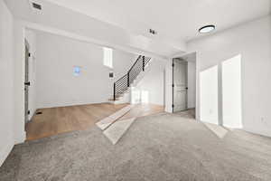 Unfurnished living room with light carpet and stairs