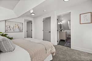 Bedroom with carpet flooring, lofted ceiling, and ensuite bathroom
