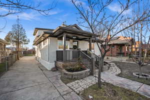 View of front of property featuring brick siding, covered porch, and a chimney