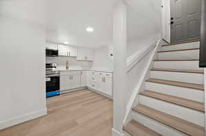 Kitchen featuring white cabinetry, stainless steel appliances, light wood-type flooring, and recessed lighting