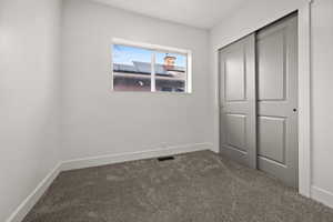 Unfurnished bedroom with dark colored carpet and a closet