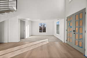 Foyer entrance with a high ceiling, light wood-style floors, and french doors