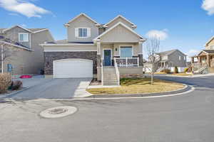 View of front of house with stucco siding, concrete driveway, a porch, stone siding, and a residential view