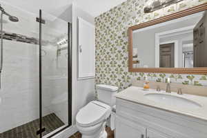 Bathroom with vanity, a shower stall, wallpapered walls, and a textured ceiling