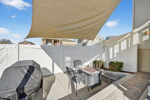 Fenced backyard with a patio area, an outdoor fire pit, and a grill