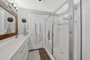 Full bathroom featuring a shower stall, vanity, and dark tile patterned flooring