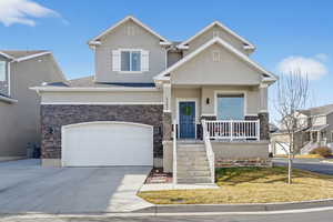 View of front of home featuring driveway, stone siding, stucco siding, a porch, and a garage