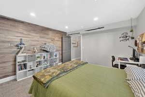 Bedroom featuring wood walls, an accent wall, light colored carpet, a desk, and recessed lighting