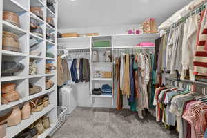 Walk in closet featuring light colored carpet