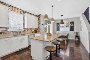 Kitchen featuring white cabinetry, a kitchen breakfast bar, decorative light fixtures, and dark laminate floors
