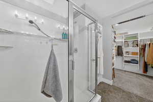 Bathroom featuring a stall shower, carpet, a walk in closet, and tile patterned floors