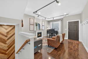 Living area with dark laminate floors, rail lighting, and a glass covered fireplace