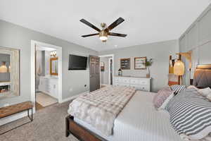 Bedroom featuring ceiling fan, light carpet, and ensuite bathroom