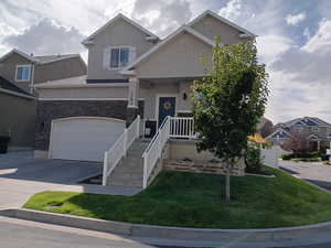 View of front of property featuring stucco siding, concrete driveway, a front yard, covered porch, and stairway