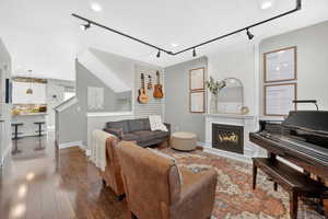 Living room featuring rail lighting, a large fire place and laminate flooring.