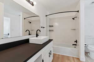Bathroom with vanity, shower / bathtub combination, and light wood-style flooring