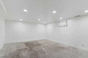 Finished basement with light colored carpet and recessed lighting