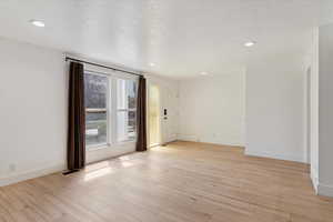 Empty room with light wood-style flooring, recessed lighting, and a textured ceiling