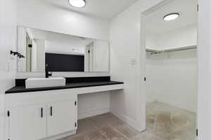 Bathroom with vanity, a walk in closet, and light colored carpet