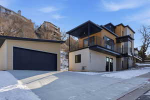 View of front of property with stucco siding, a garage, an outbuilding, and a balcony