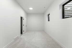 Corridor featuring light carpet and baseboards
