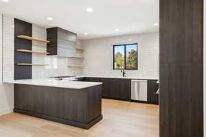 Kitchen featuring open shelves, a peninsula, stainless steel dishwasher, light wood finished floors, and tasteful backsplash