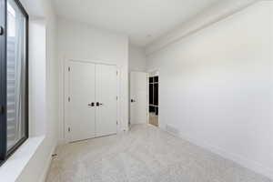 Unfurnished bedroom with light carpet and a closet