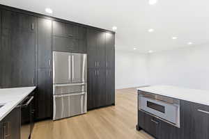 Kitchen featuring stainless steel appliances, light wood-type flooring, modern cabinets, recessed lighting, and light stone counters
