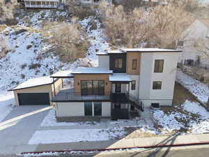 Contemporary house featuring a garage, stucco siding, concrete driveway, and an outbuilding
