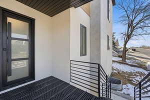 Snow covered property entrance featuring stucco siding and a patio area