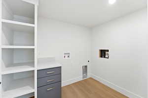 Washroom with washer hookup, light wood-style flooring, electric dryer hookup, and cabinet space
