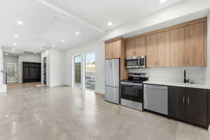 Kitchen featuring appliances with stainless steel finishes, modern cabinets, finished concrete floors, open floor plan, and recessed lighting