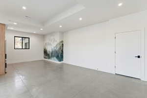 Unfurnished room with recessed lighting, finished concrete flooring, and a tray ceiling