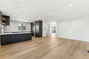 Kitchen featuring open shelves, open floor plan, backsplash, light wood-type flooring, and modern cabinets