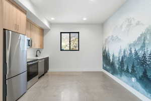 Kitchen featuring appliances with stainless steel finishes, concrete flooring, light brown cabinetry, modern cabinets, and recessed lighting