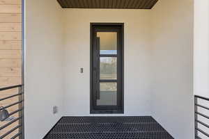 Doorway to property featuring stucco siding