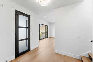 Hallway with light wood-style flooring and recessed lighting