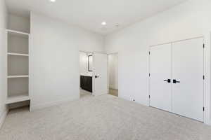 Unfurnished bedroom featuring light colored carpet, ensuite bathroom, recessed lighting, and a closet