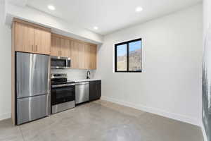Kitchen featuring appliances with stainless steel finishes, concrete floors, light brown cabinetry, modern cabinets, and recessed lighting